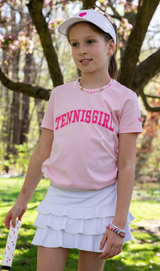 Girl wearing Love Set Match pink tennis girl t-shirt, white tennis visor and white tennis ruffled tennis skirt from Love Set Match tennis wear
